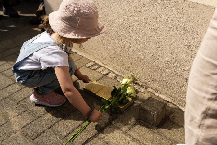 Kind legt Blumen auf Stolpersteine