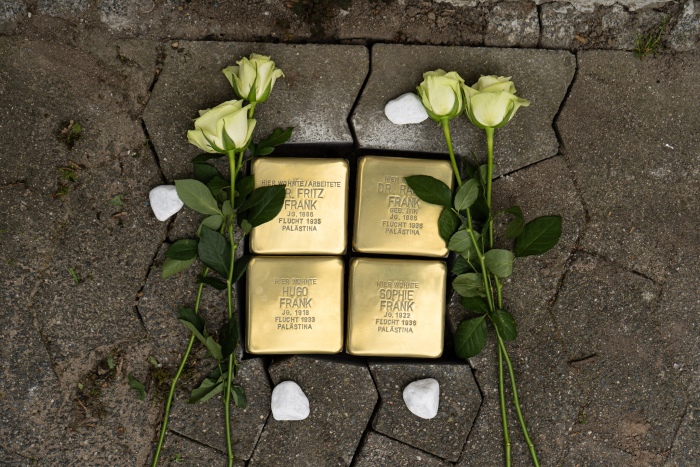 4 Stolpersteine. Blumen liegen darauf und Steine daneben